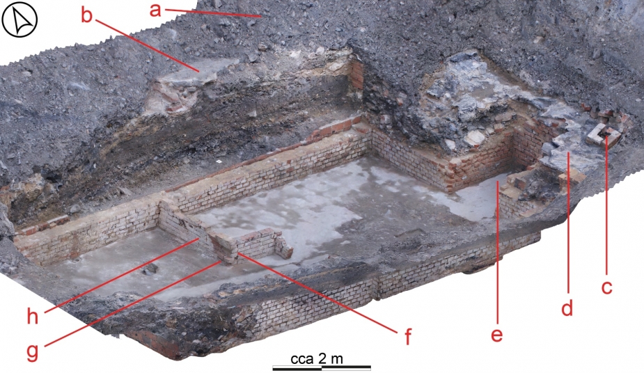 Pohled na situaci odkrytého sklepa táborové kuchyně: a – navážka překrývající reliky tábora; b – betonová podlaha přízemních prostor budovy kuchyně; c – nadstřešní část cihlového komína budovy snesená spolu se střešní krytinou při demolici budovy; d – shozená střešní asfaltová krytina; e – šachta pro skládání zboží ústící na povrch dvora mimo nadzemní půdorys stavby; f – zednicky nesprávně provedené nároží příčky sklepa; g – otisk dřevěného či železného schodiště ve výmalbě sklepa; h – výmalba sklepa vápenným nátěrem, v níž se dochovalo několik tužkou psaných nápisů souvisejících snad s evidencí uloženého zboží (vícesnímková fotogrammetrie P. Hasil)
